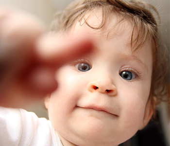 Kleinkind deutet mit Finger auf Kamera.