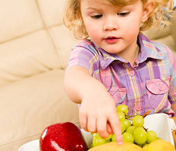 Kind zeigt mit Finger auf Obst