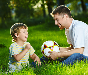 Vater sitzt mit Sohn auf Wiese